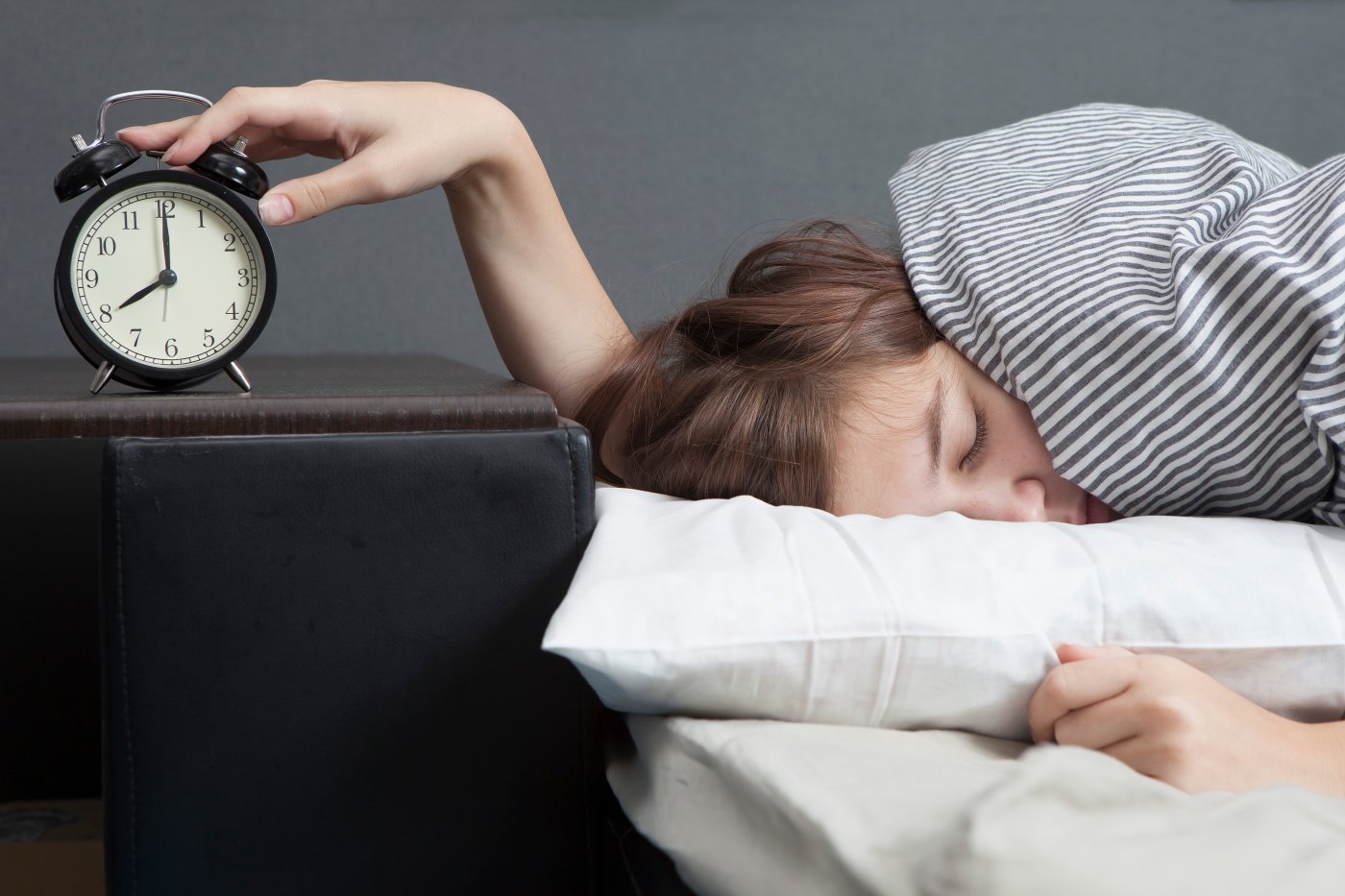 Sleeping person with hand on alarm clock