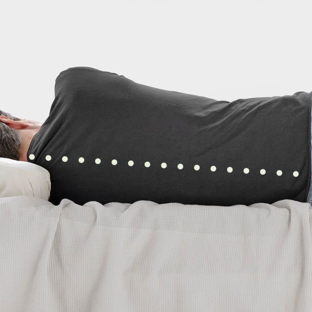 A man lies in bed on his side with a straight spine