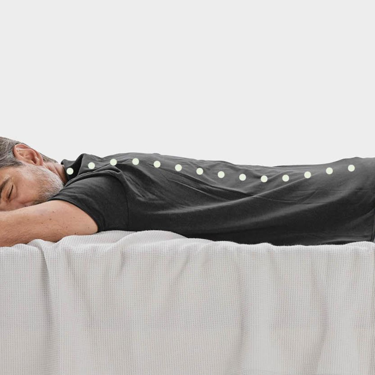 A man is lying on his stomach in bed