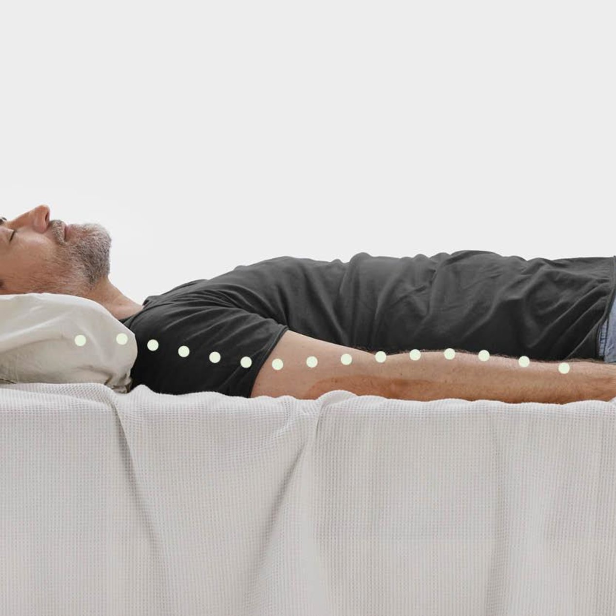 A man is lying in bed with his back straight