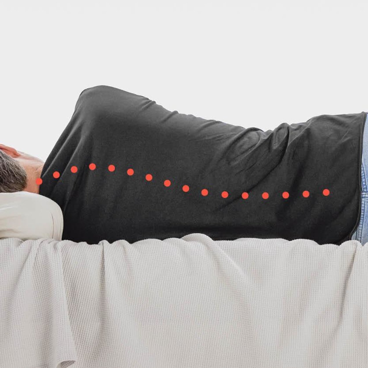 A man is lying in bed on his side with a curved spine