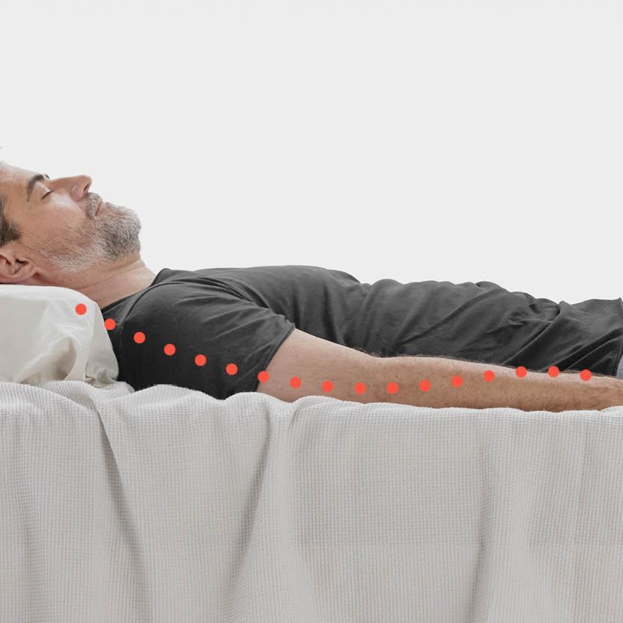 A man is lying in bed with his back arched