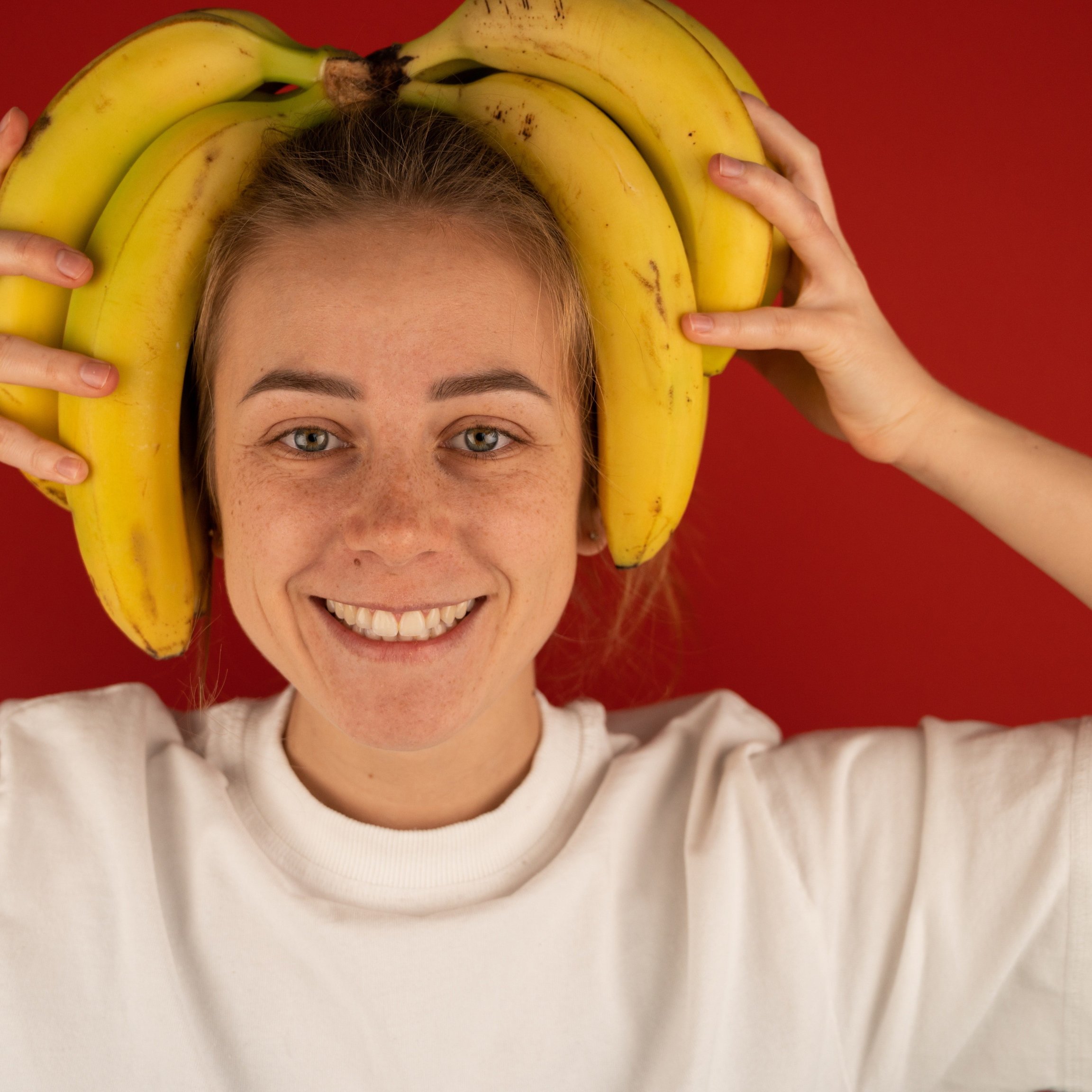 Lächelnde Frau hält sich eine Banane wie Kopfhörer an die Ohren.