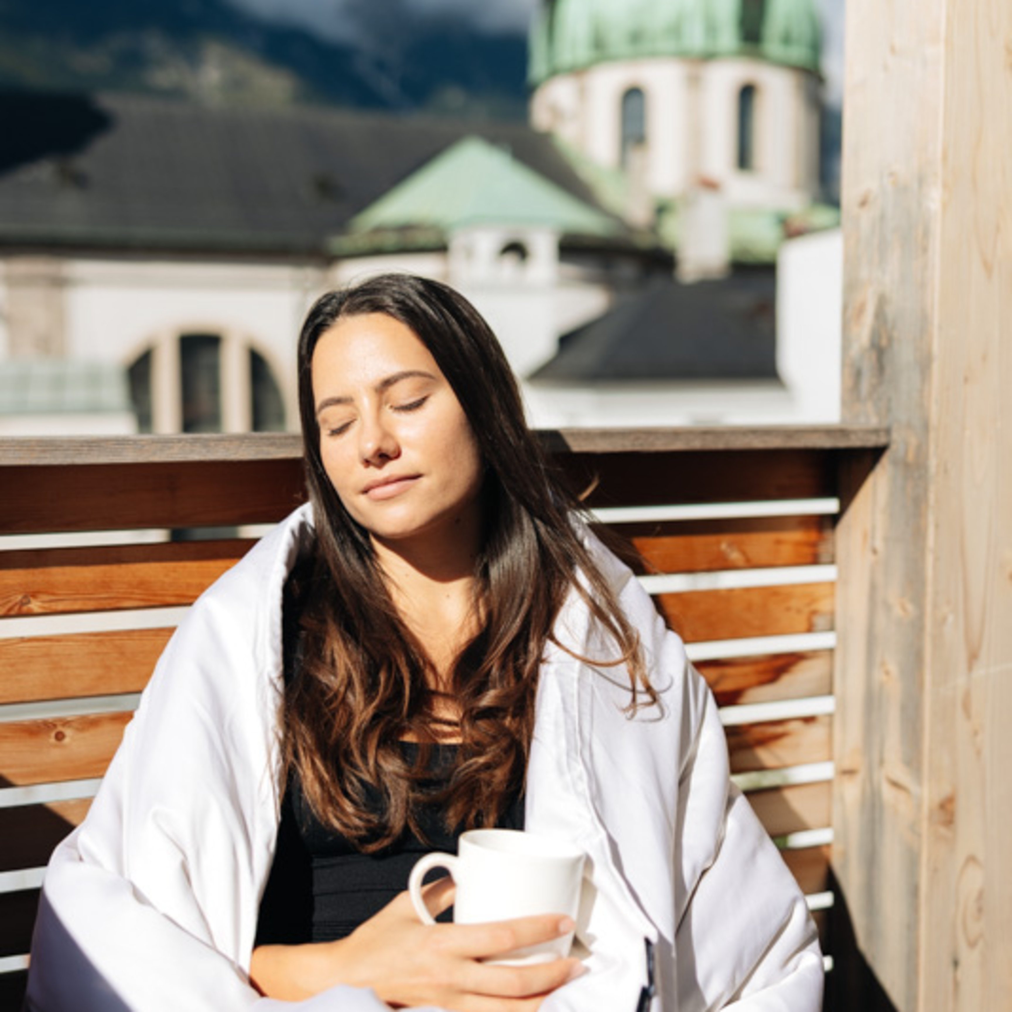 Woman in the sun on a balcony with a blanket