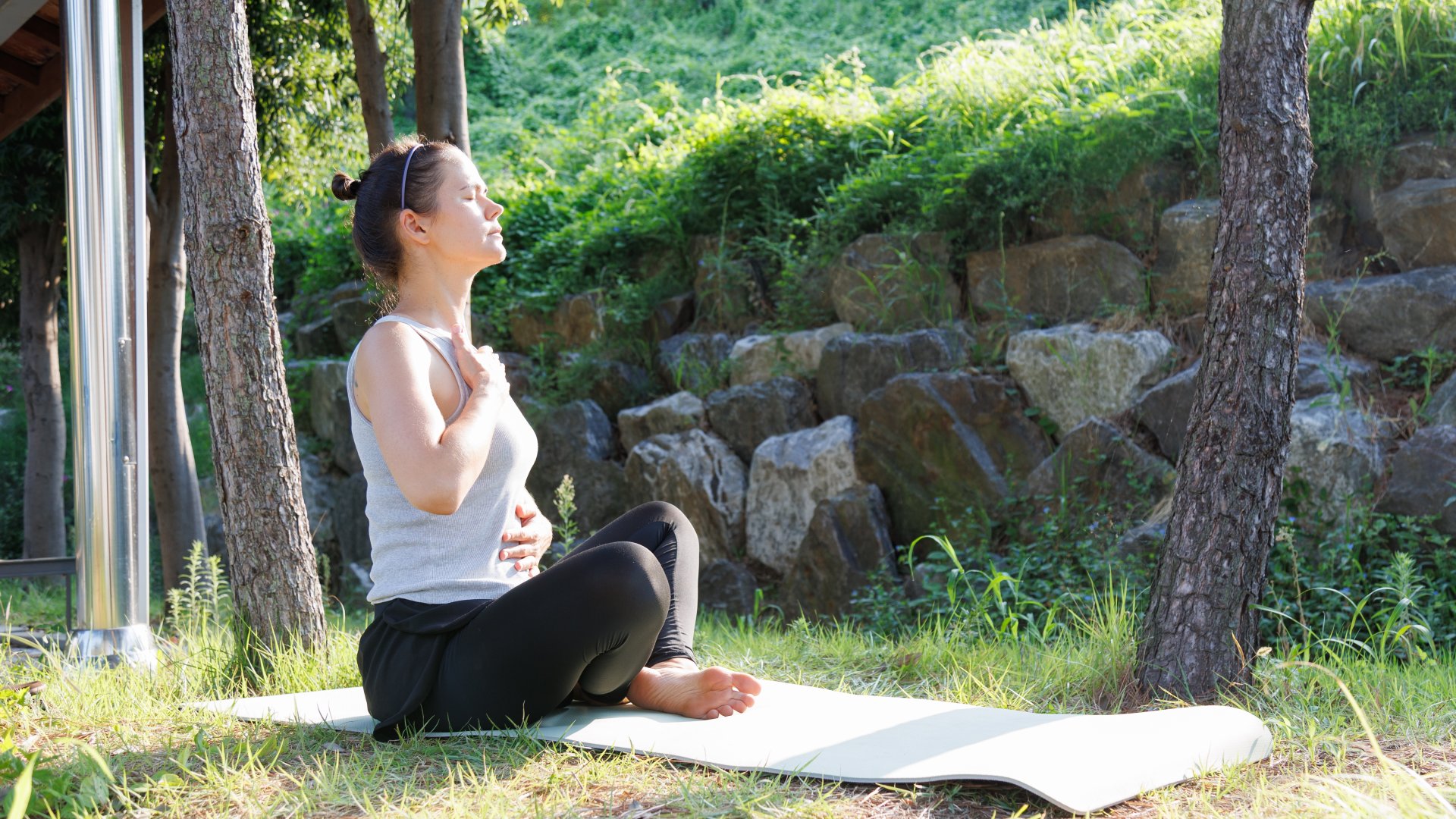 Breathing exercise during morning wellness practice in a quiet park. People sitting on yoga mat, focusing on deep breathing, calm mind and emotional balance in nature.