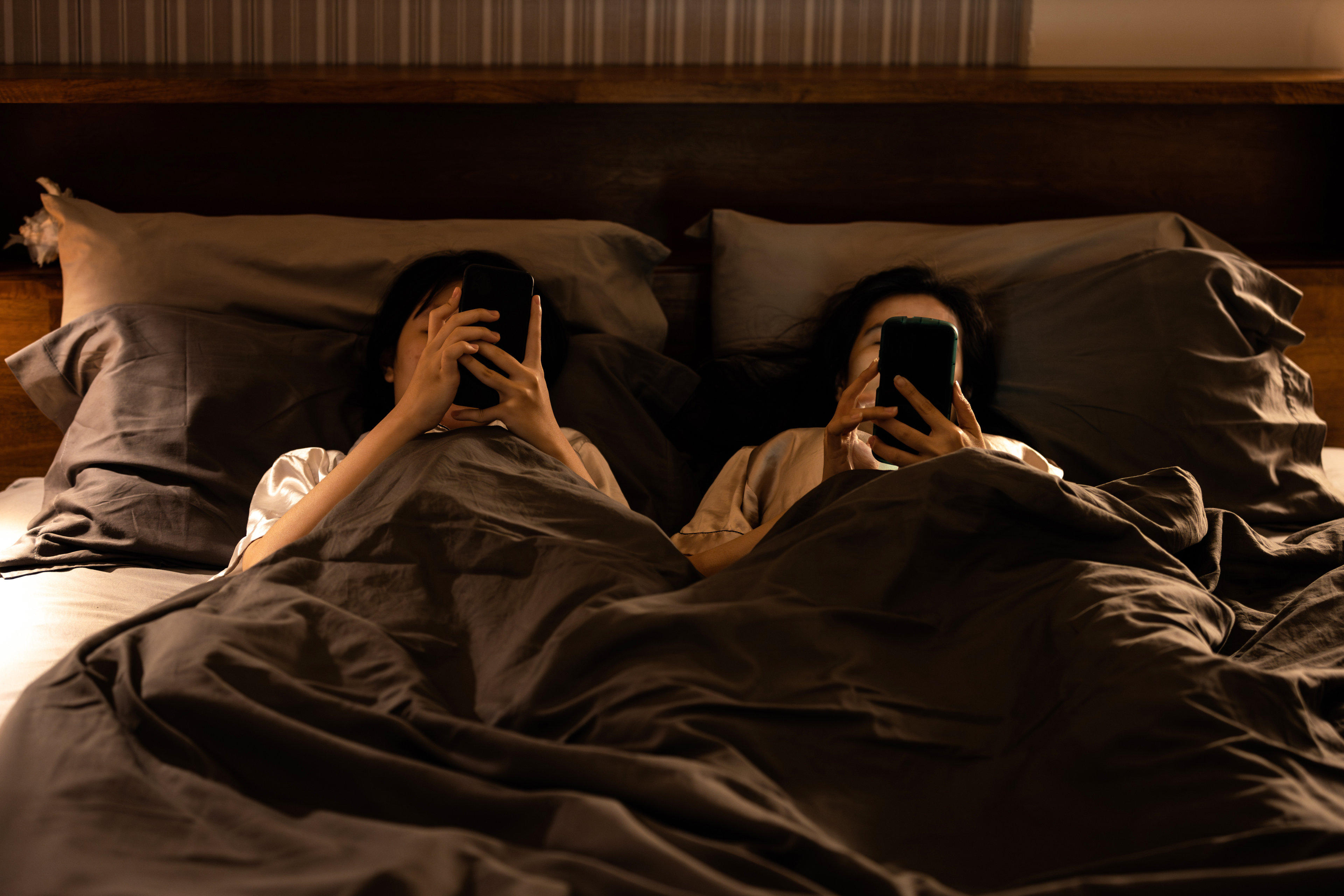 Two people with cell phones in bed