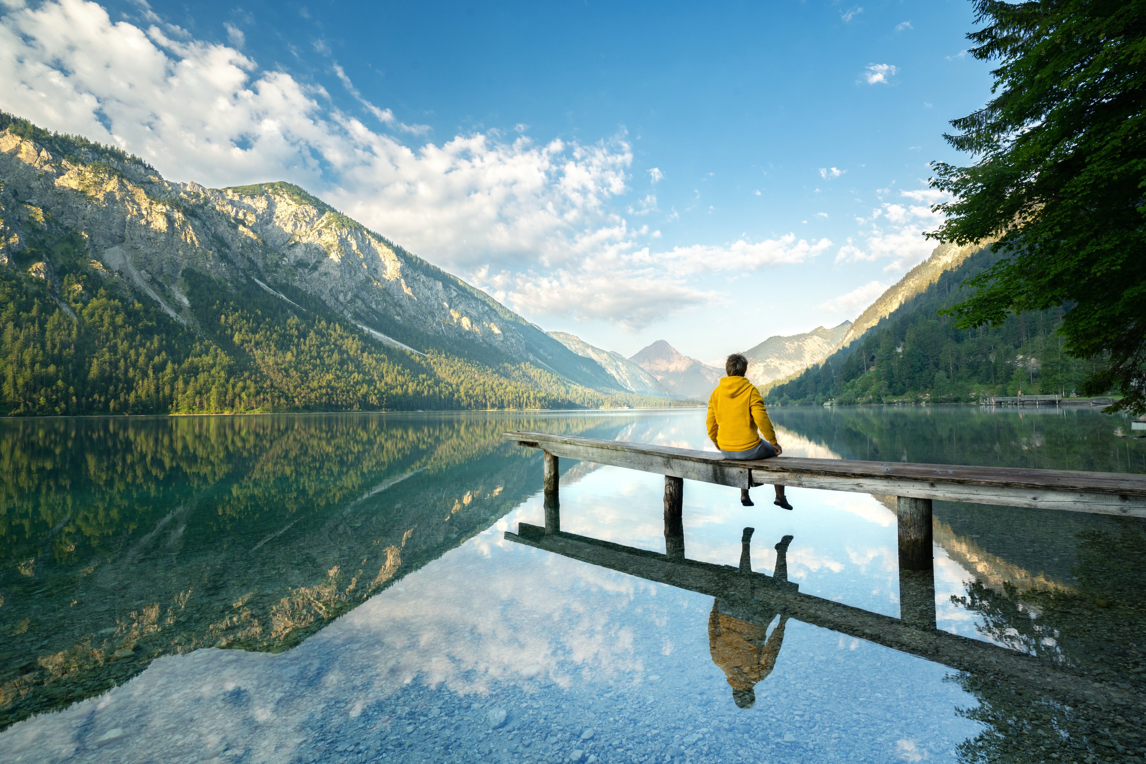 Offline: A man sits on a dock by a mountain lake