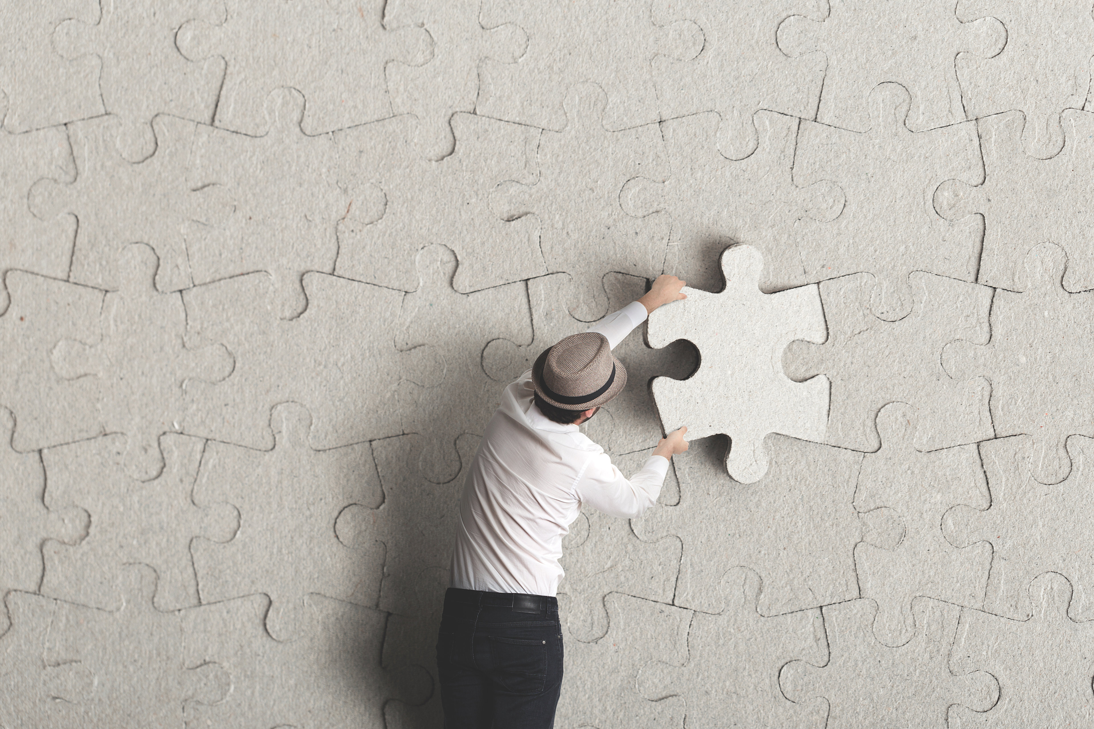 A puzzle that is almost complete, with a missing piece in a person’s hand