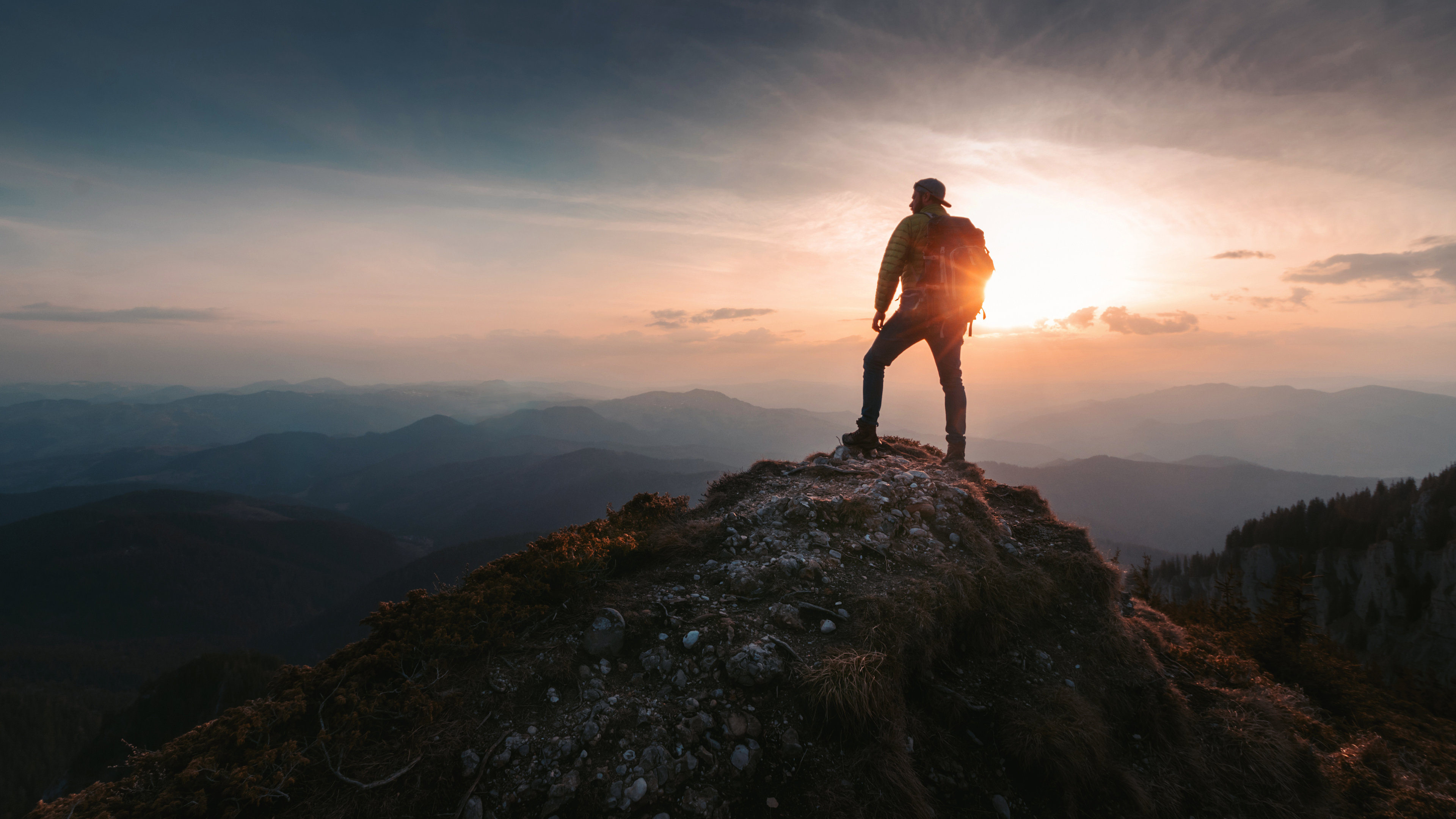 Someone standing alone on a mountain peak, looking out at the view