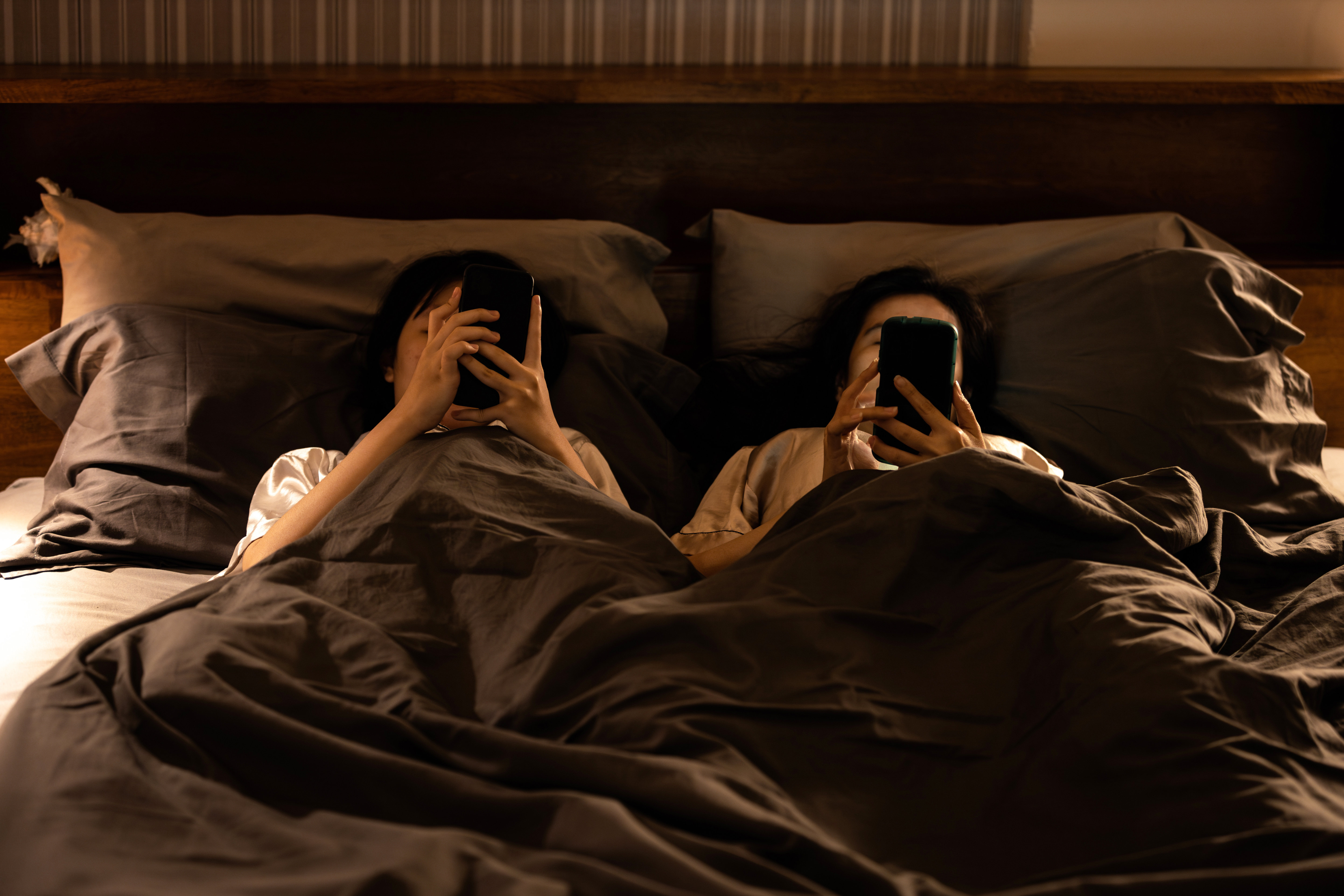 Two people with cell phones in bed