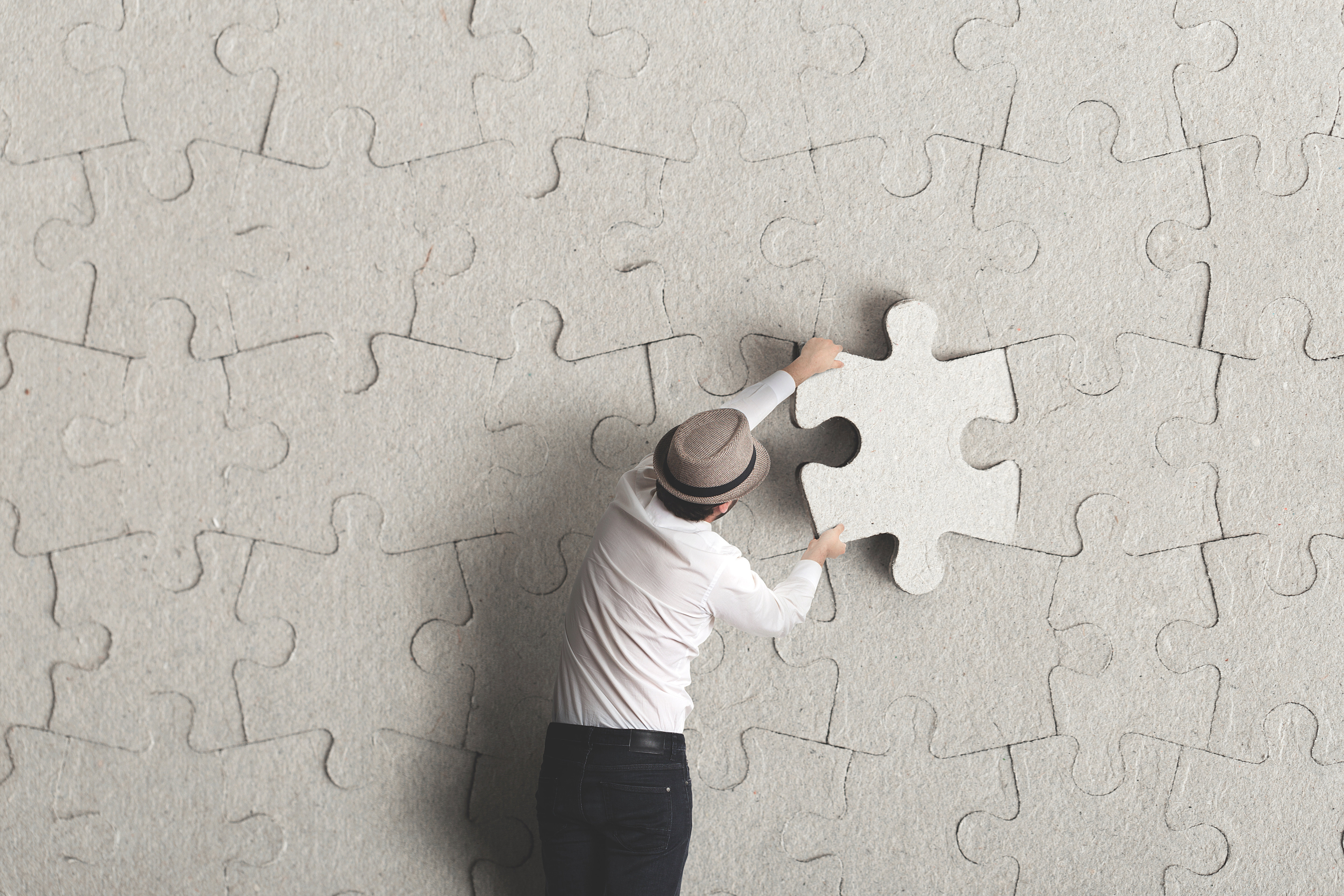A puzzle that is almost complete, with a missing piece in a person’s hand