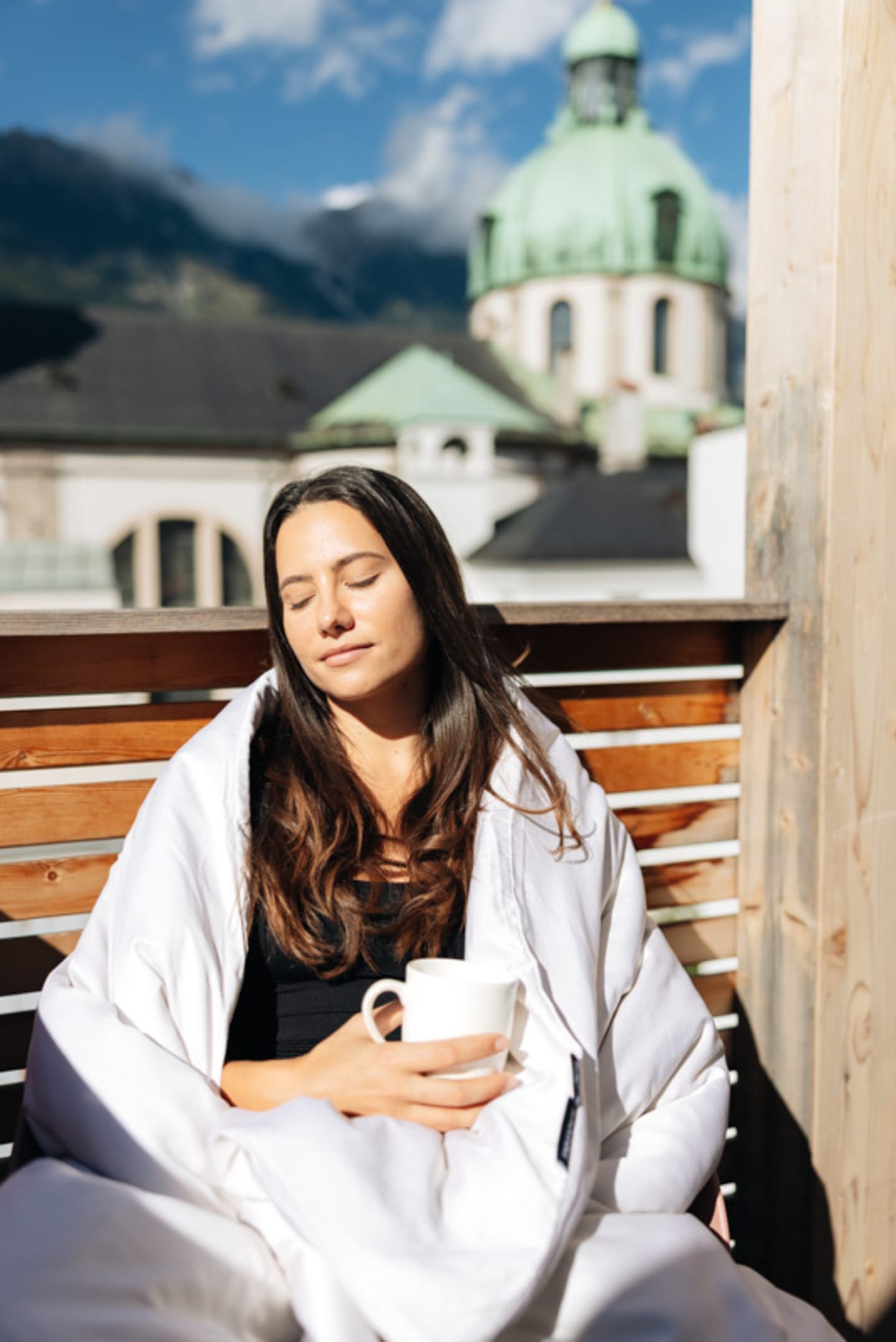 Frau in der Sonne auf Balkon mit Decke
