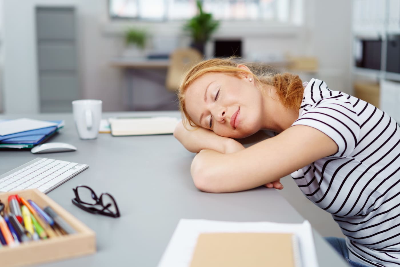 Frau beim Powernap am Schreibtisch