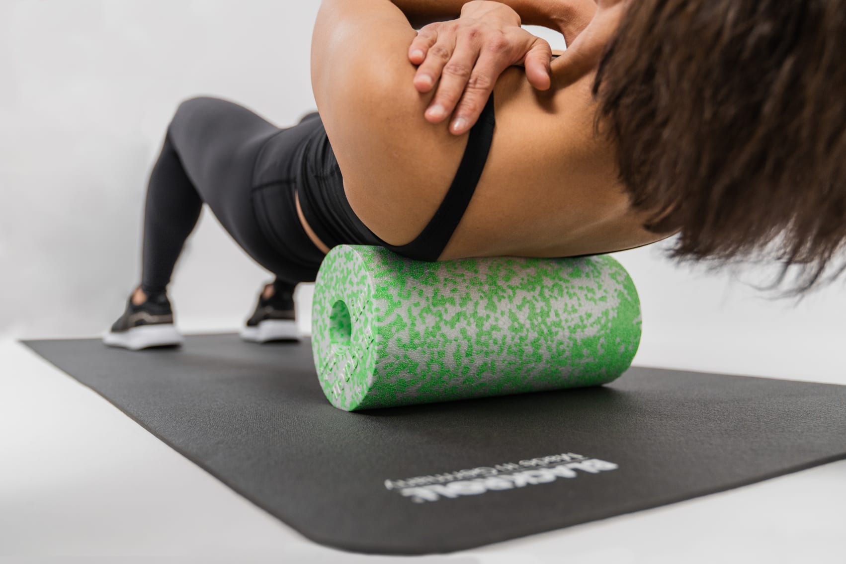 Une femme se masse le dos avec un rouleau de fascia MED souple