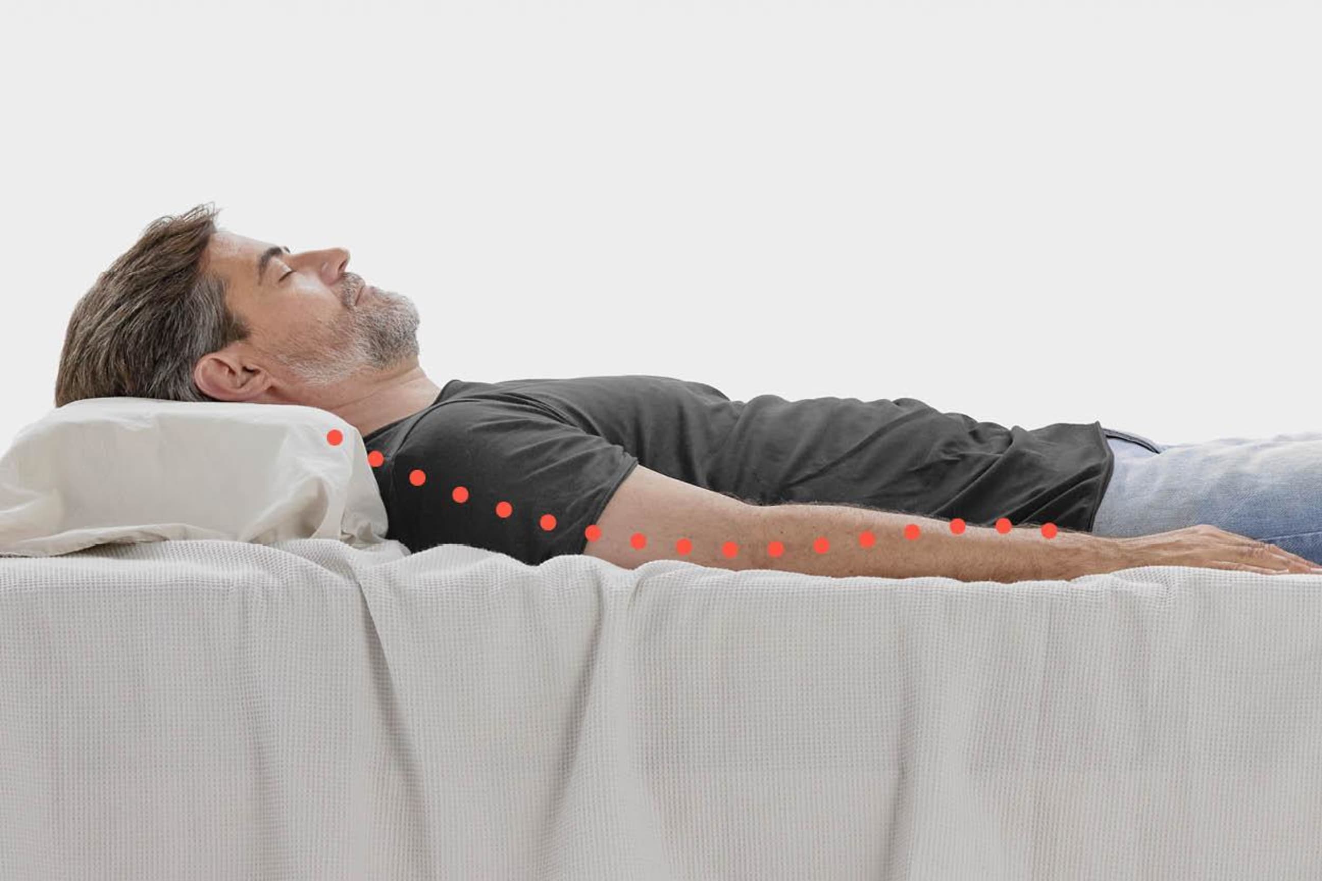 Un homme est couché dans un lit avec le dos courbé