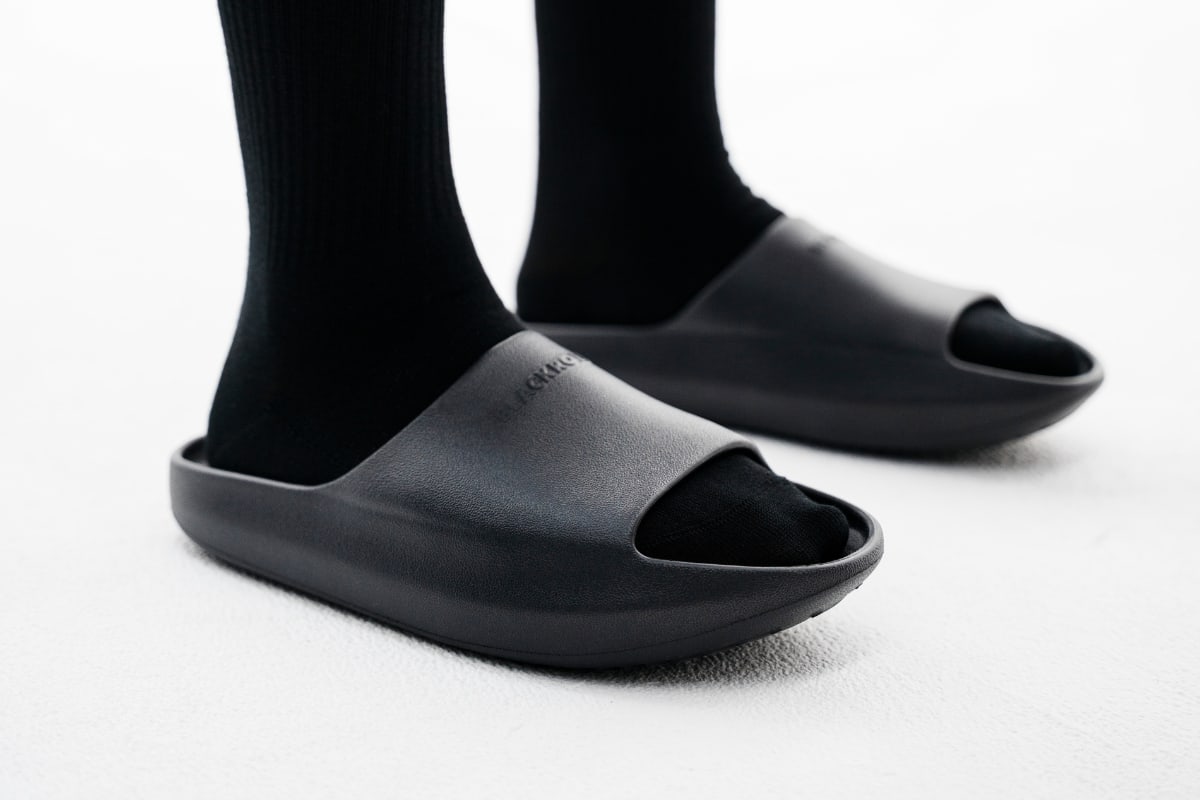 Nahaufnahme von schwarzen RECOVERY SLOPES CORE an den Füßen mit schwarzen Socken.