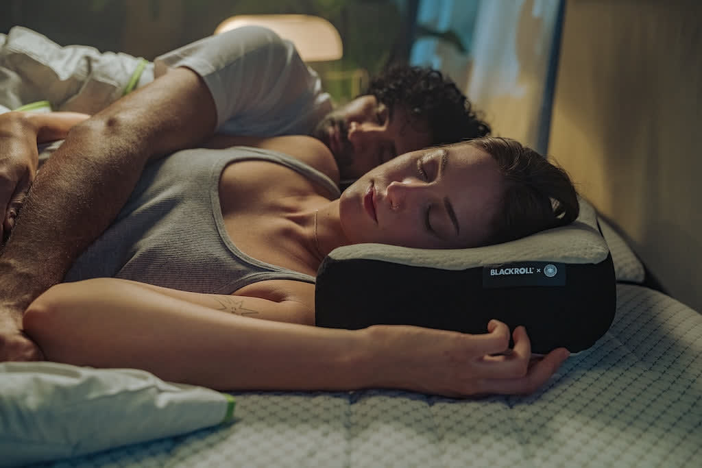 Frau schläft auf dem BLACKROLL Recovery Pillow mit Pillow Case, während eine zweite Person im Bett liegt