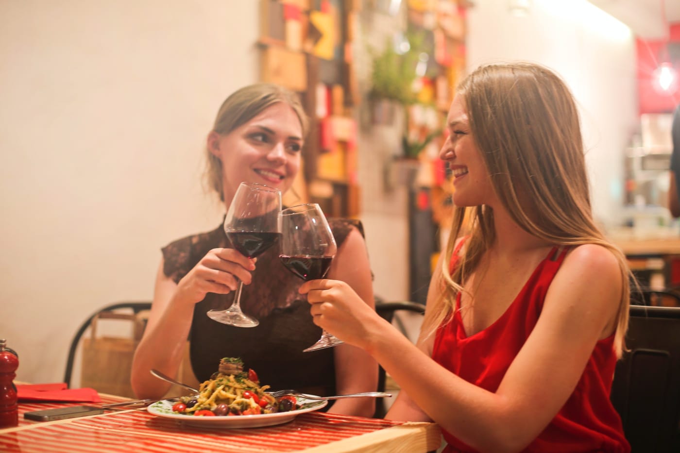 Zwei Frauen beim Essen, die anstoßen