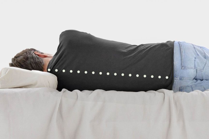 Ein Mann liegt im Bett in Seitenlage mit gerader Wirbelsäule